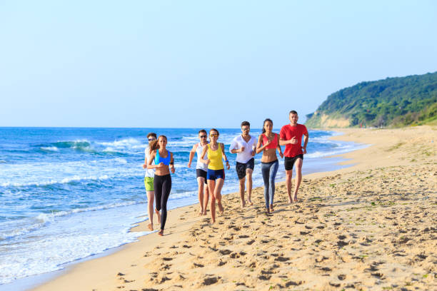 Group of people running on beach with cityscape in background. May 4, 2025 Constanta Romania.