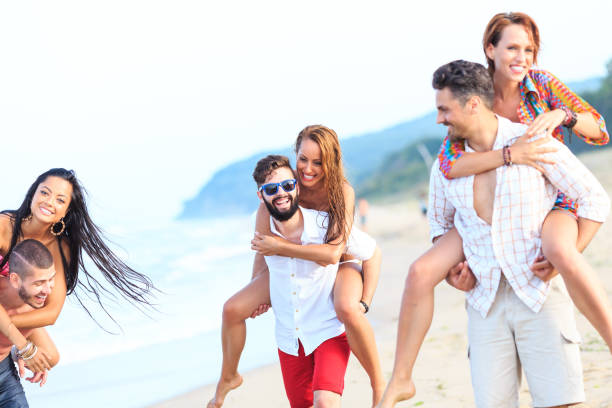 istock Happy couples having fun in piggyback ride on beach 656527418