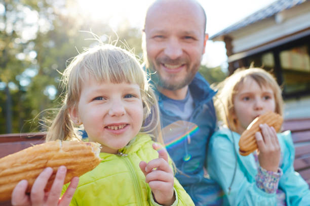 istock Little sisters eating hotdogs in park 656534800