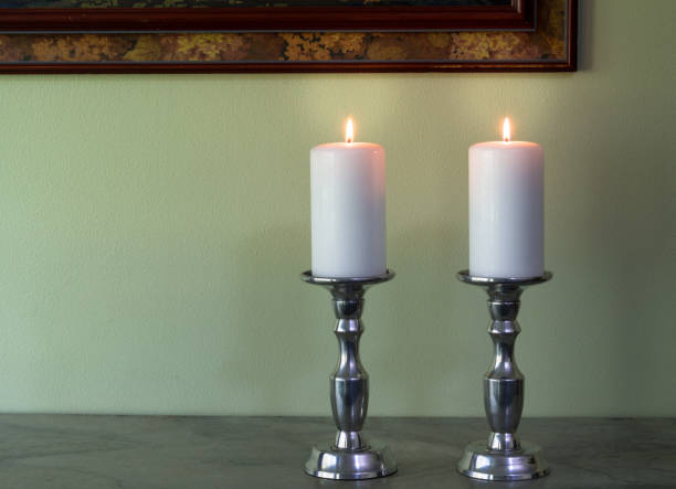 istock Two lit white candles in canelabra against green wall texture background 656547094