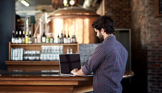 Shot of a young man using a laptop in a bar