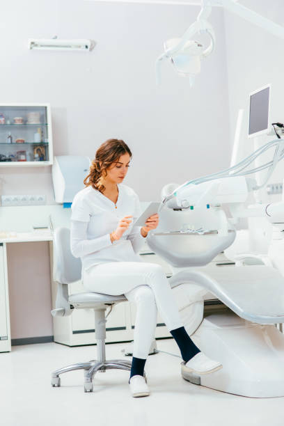 Dentist working on a tablet Female dentist working on a tablet at a dental office. tablet pc and digital hospital tools stock pictures, royalty-free photos & images