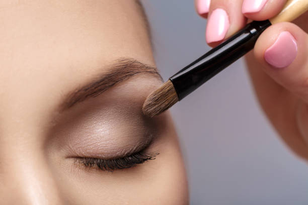 truccatore applicare pennello per il trucco per gli occhi. trucco per la ragazza. ombretto marrone. da vicino - face powder eyeshadow make up make up brush foto e immagini stock