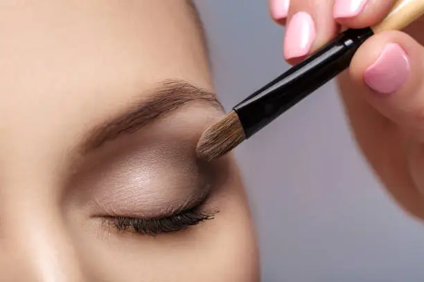 Photo of makeup artist apply makeup brush for eyes. makeup for young girl. brown eye shadow. close up