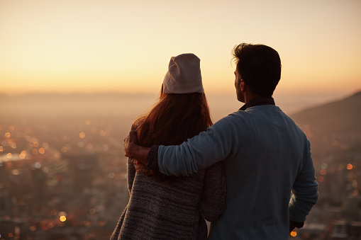 Rearview shot of an affectionate  young couple admiring a city view at dawn