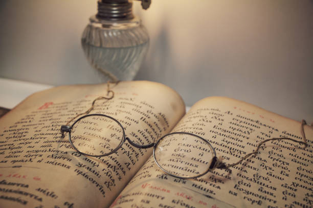 Opened vintage book (Psalter, old russian language) with old eyeglasses, light of kerosene lantern (Betty lamp), closeup