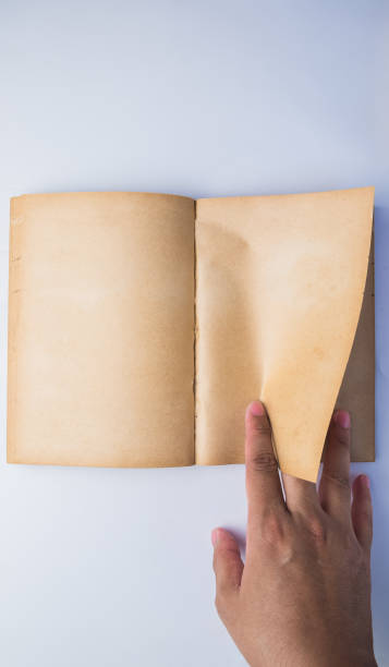 istock A man's hand turn old book page, view from above, isolated 656571668