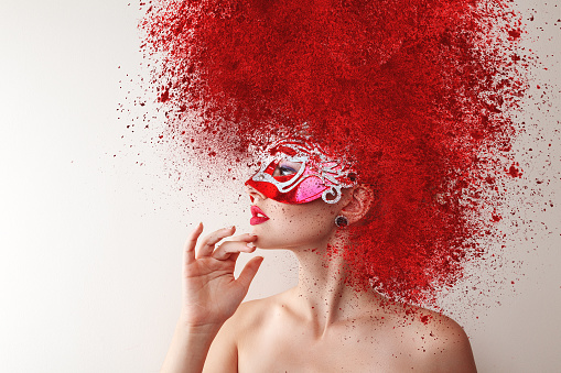 Young fashion model with carnival mask and exploding powder hairstyle