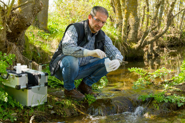 View of a Biologist take a sample in a river. Scientist and biologist hydro-biologist takes water samples for analysis. biologist stock pictures, royalty-free photos & images