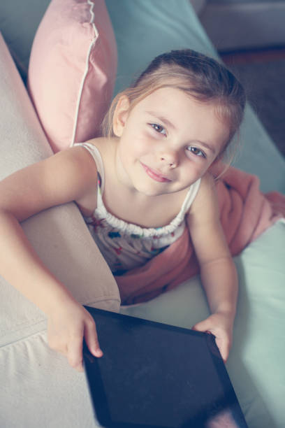 istock Young girl using a tablet sitting on the couch. 656603202