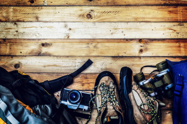istock travel accessories set on wooden background: old hiking leather boots, backpack, map, Sleeping bag,binocular,vintage film camera 656622706