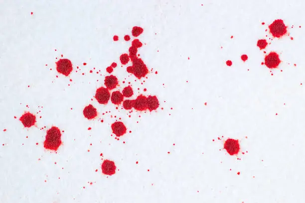 Red blood drops on white snow-liked felt background. Criminal or violence concept