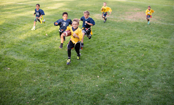 jeune joueur de football de drapeau de garçon fonctionnant pour un touchdown - running back photos photos et images de collection