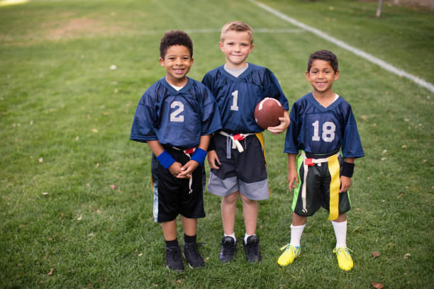 Three Young Boys and Teammates Play Flag Football stock photo