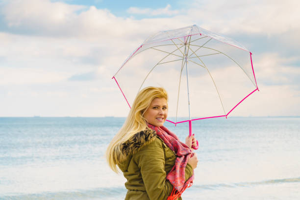 istock Woman standing with transparent umbrella on beach 656642118