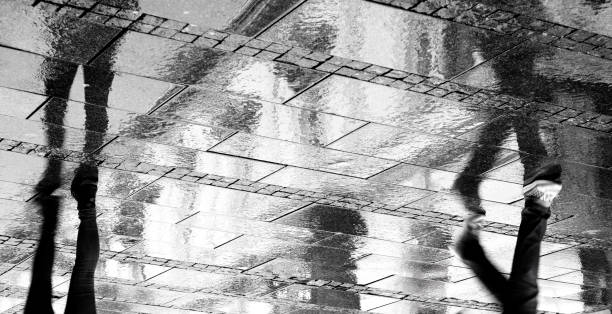 Rainy refletions of two person on the city street, upside down in black and white stock photo