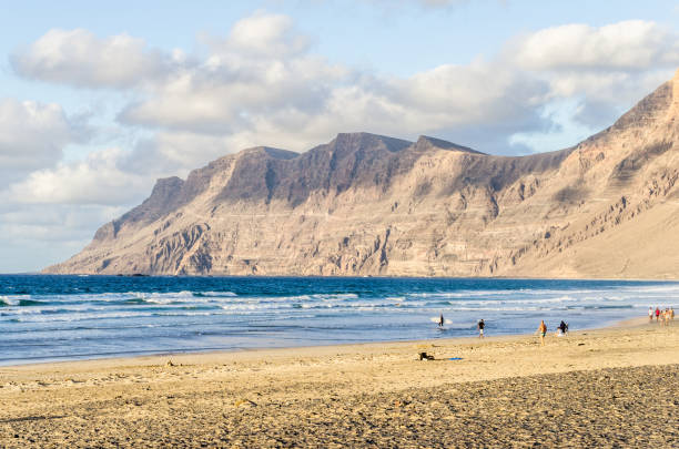 flare-touristen caleta de famara strand lanzarote klippe - famara stock-fotos und bilder