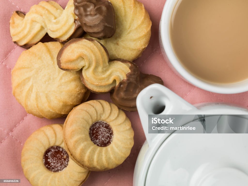 Tea and a Selection of Biscuits Tea and a Selection of Biscuits With a Teapot Against a Pink Background Tea - Hot Drink Stock Photo