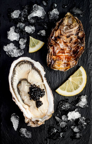 istock Oysters with black sturgeon caviar and lemon on black slate stone background. Top view, flat lay 656661950