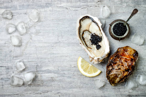 istock Opened oysters with black sturgeon caviar and lemon on ice on grey concrete background. Top view, flat lay, copy space 656662062