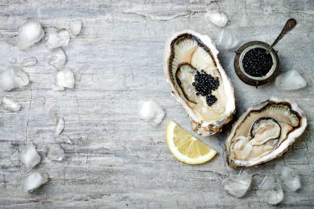 istock Opened oysters with black sturgeon caviar and lemon on ice on grey concrete background. Top view, flat lay, copy space 656662064