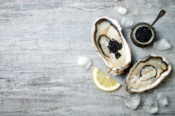 istock Opened oysters with black sturgeon caviar and lemon on ice on grey concrete background. Top view, flat lay, copy space 656662330
