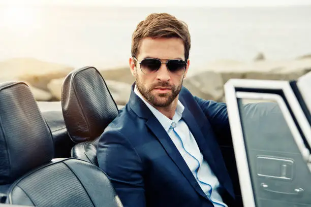 Serious man suited in sports car, portrait