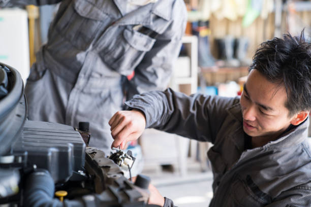 Two mechanics working together in an automotive repair shop stock photo