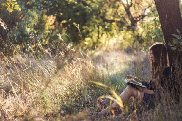 istock Girl reading book in summer forest 656680254