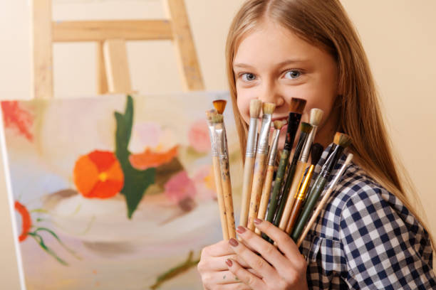 istock Charming girl holding paintbrushes in the art studio 656700222
