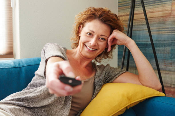 istock Happy woman in comfortable apartment holding remote control 656711420