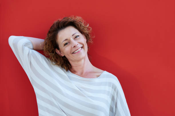 istock Woman standing with hand behind head by red wall 656711542