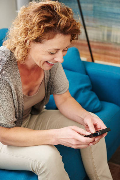 istock Woman smiling at home writing text on smart phone 656711620