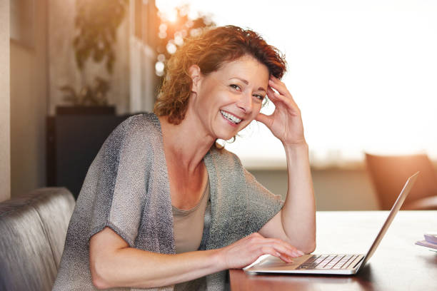 Woman sitting at table with smiling  with laptop stock photo
