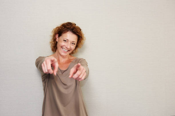 Smiling older woman pointing fingers stock photo