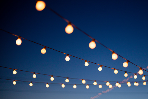 String lights hang outdoors on a summer evening.