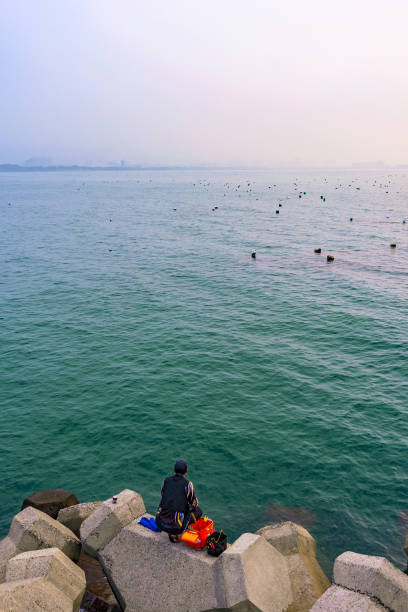Lone fisherman with his fishing rod on the beach at night