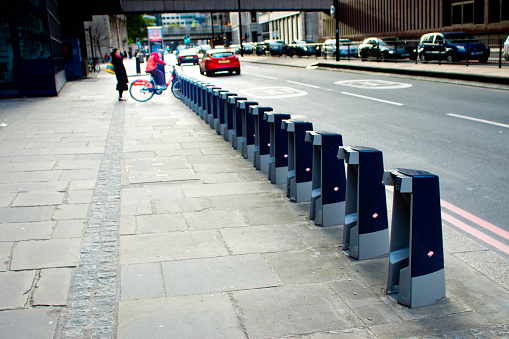 The last Santander hire bike being taken from the bike rack in central London. This image shows a row of empty racks and one bike at the very end of the rack being removed by a rider.