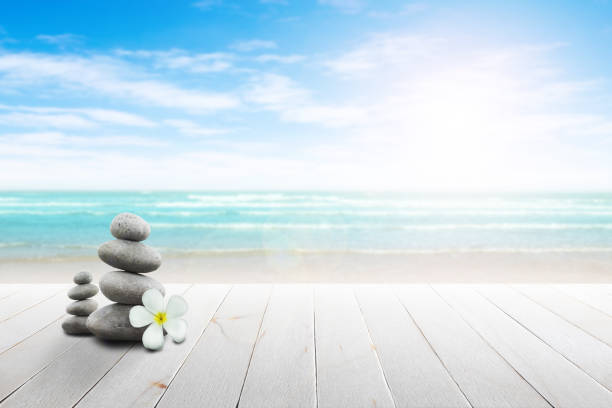 istock Stack of pebble stones and Plumeria wooden surface. 656750572