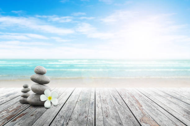 istock Stack of pebble stones and Plumeria wooden surface. 656750772