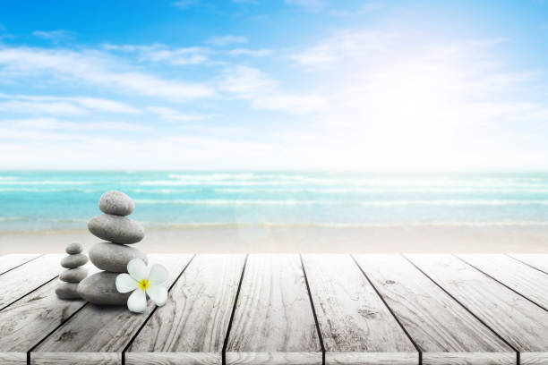 istock Stack of pebble stones and Plumeria wooden surface. 656750952
