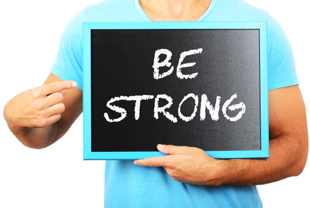 homem segurando o quadro-negro nas mãos e apontando a palavra be strong - livestrong - fotografias e filmes do acervo