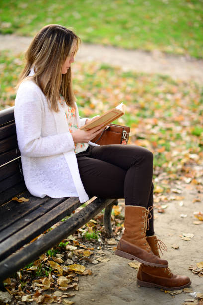 istock Woman reading a book at bench in autumn park 656752758