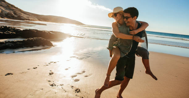istock Man giving piggyback ride to girlfriend on beach 656757536