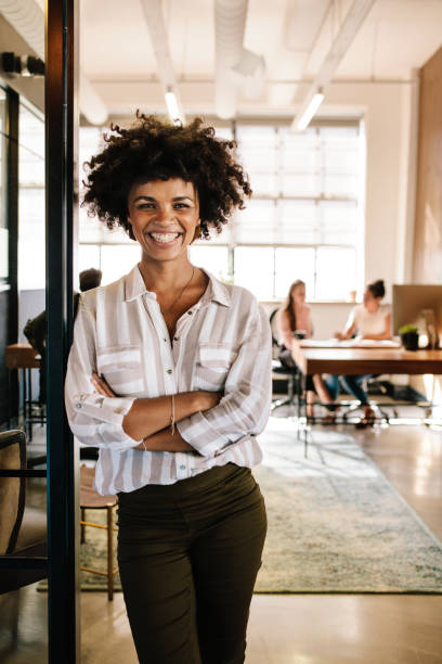 mulher jovem sorridente, inclinando-se para a porta do escritório - door office business women - fotografias e filmes do acervo