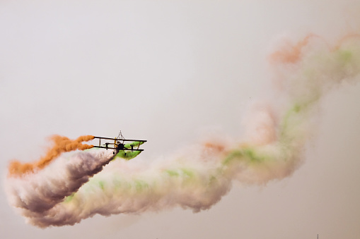 Bangalore, Karnataka, India - 02/16/2017 :  Taken this picture at Aero India 2017 of a biplane entertaining spectators by creating the Indian Flag using the smoke. Taken this picture from a distant. The airshow has been organised at Bangalore in India.