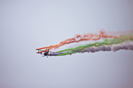 Bangalore, Karnataka, India - 02/16/2017 :  Taken this picture at Aero India 2017 of a biplane entertaining spectators by creating the Indian Flag using the smoke. Taken this picture from a distant. The airshow has been organised at Bangalore in India.
