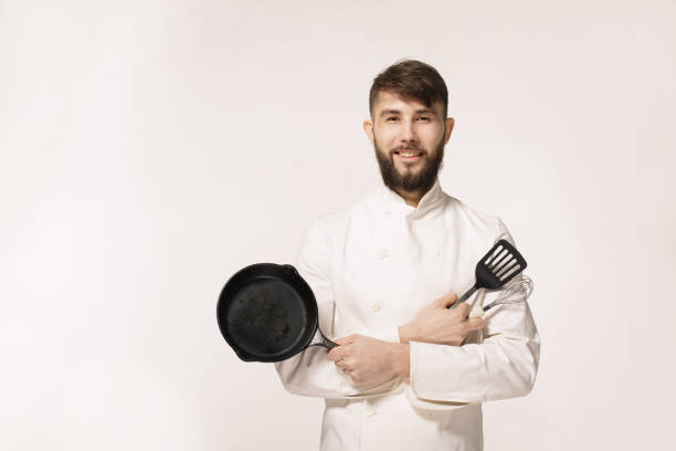 istock Confident chef. Cheerful young African chef in white uniform keeping arms crossed and smiling while standing against grey background 656793374