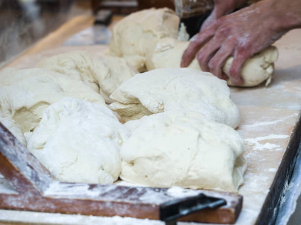 istock Baker kneading dough. Homemade bread. Hands preparing bread dough on a wooden table. Preparing traditional homemade bread. Man hands kneading fresh dough for making bread 656803746