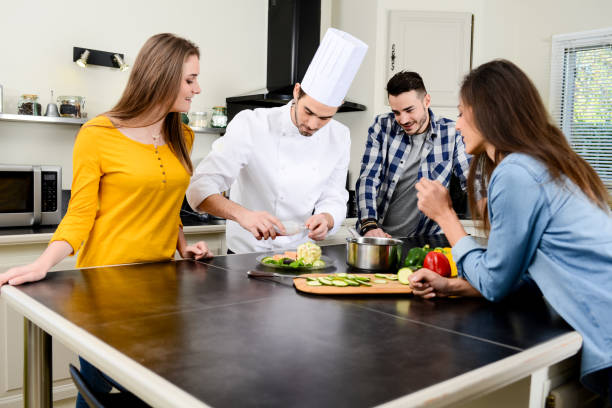 professional personal chef cook in customer's private kitchen house giving a cooking lesson to young people at home